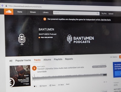 A computer screen displaying a website of an audio streaming service. The website showcases a podcast called BANTUMEN with the description 'Pro Unlimited.' There is a navigation bar with options including Home, Stream, Library, and more. A music wave graphic is visible below, along with a play button, social media interaction options such as re-post, share, and add to playlists. A banner at the top talks about fan-powered royalties, and there is a COVID-19 information widget to the side.